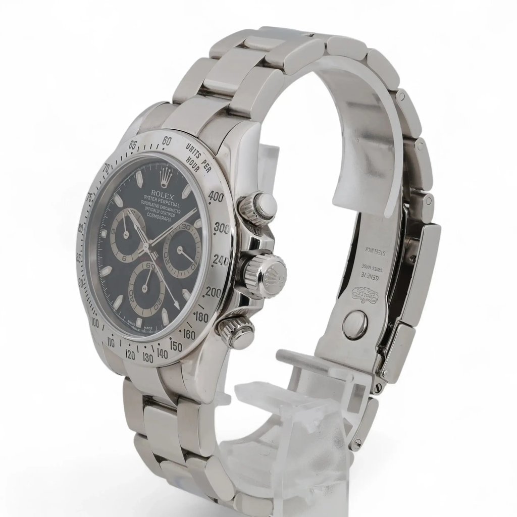An image of a pre-owned men's Rolex wristwatch, positioned at a three-quarter angle, slightly elevated to showcase its features. The watch has a stainless steel band and a black dial with three subdials, including a small seconds subdial. The chronograph and luminous hands are visible, and the watch is displayed on a transparent stand, emphasizing its elegant design. The photo captures the watch from a moderate distance, highlighting both the face and the side profile.