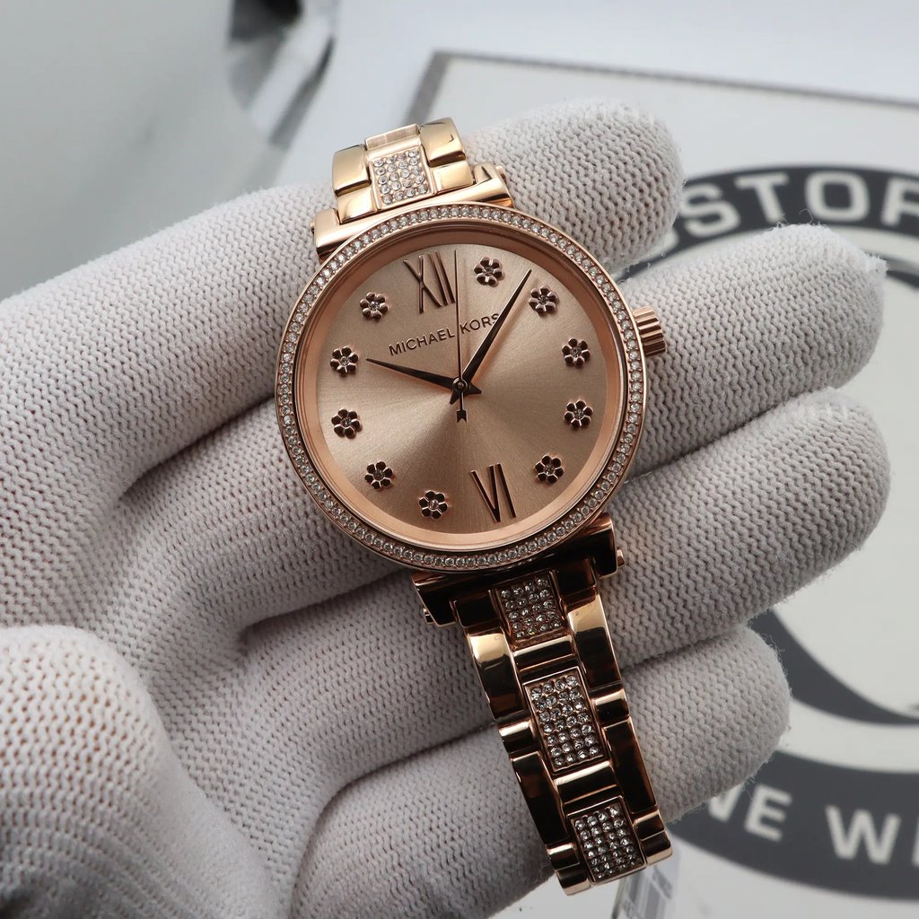 An image of a Wristwatch by Michael Kors. This New With Defects item is designed for Women, featuring a Dress/Formal style. It has a Quartz movement and an Analog display with a Gold dial color. The indices include 12-Hour Dial,Non-Numeric Hour Marks. The band is made of Stainless Steel and the case is made of Stainless Steel. The watch has a Round shape with a case size of 36 mm and a case thickness of 9 mm.