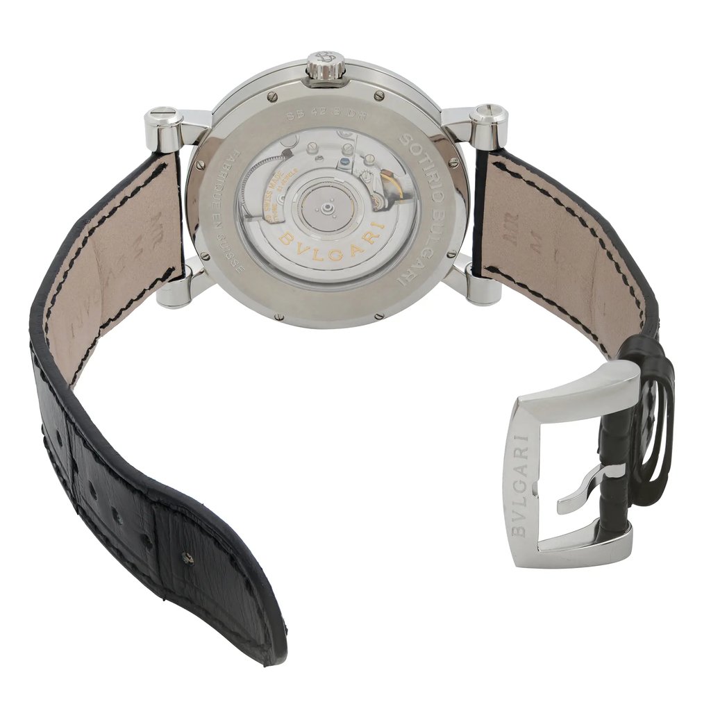 An image of a wristwatch displayed from the back view, showcasing its open clasp. The watch is positioned upright, with a focus on the exposed mechanism and inscriptions on the case back. The angle allows a clear view of the intricate inner workings and the leather strap's texture. Photographed at a close distance, highlighting the details of the display model.