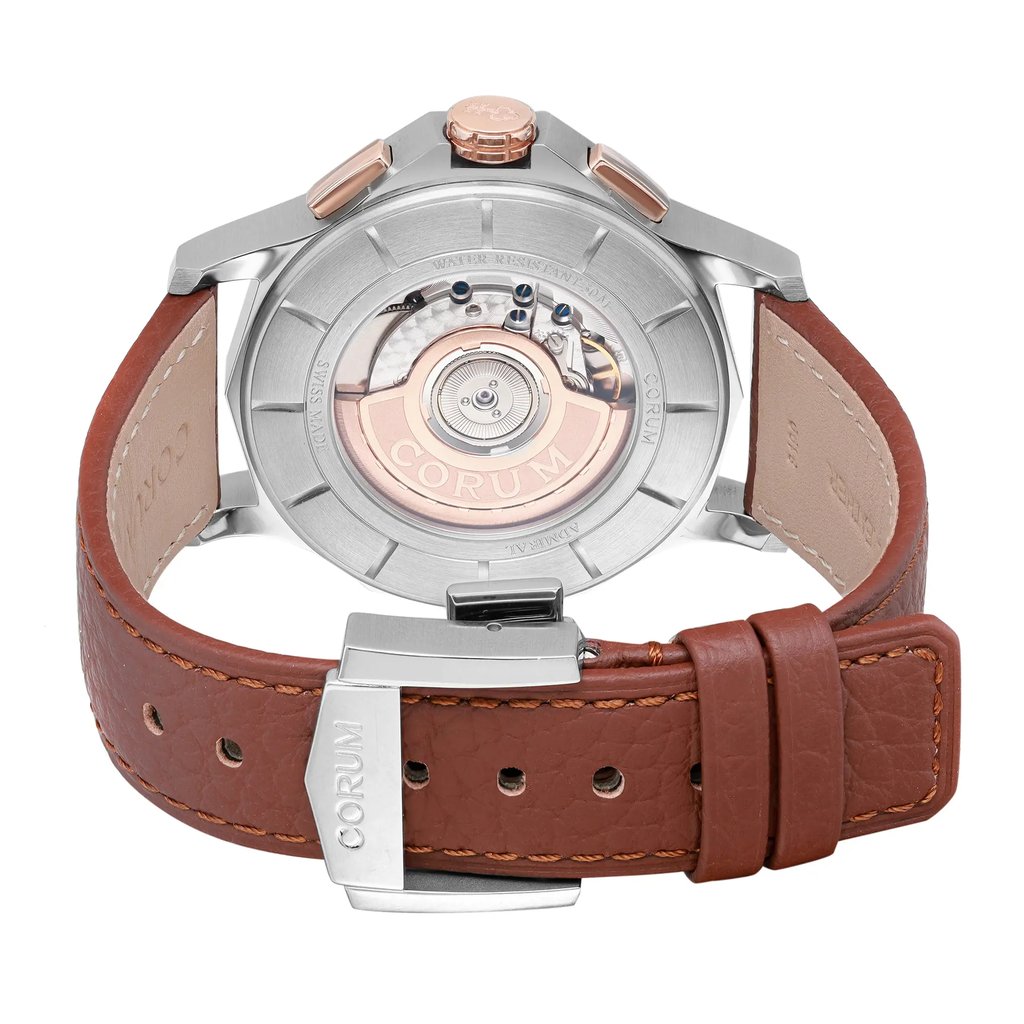 An image of a wristwatch showcasing the back view. The focus is on the closed clasp and the visible mechanical movement. The watch has a brown leather strap, and the metal parts of the clasp are engraved with the brand name. The angle is directly from behind, capturing the intricate details of the display model at a close distance.
