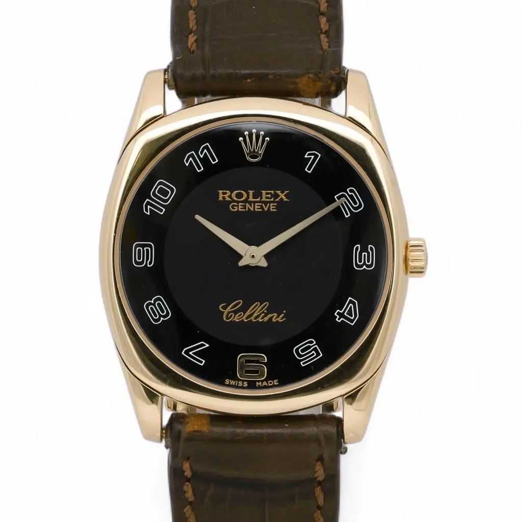 An image of a pre-owned men's Rolex wristwatch, viewed from a straight-on angle at a close distance. The watch features a 18k rose gold case with a black dial and white numerals. The brand name "Rolex" and "Cellini" are prominently displayed on the face. The timepiece is fitted with a brown leather strap.