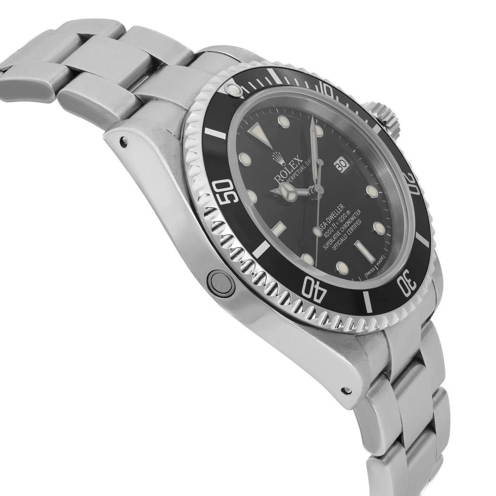 An image of a pre-owned men's luxury Rolex wristwatch viewed from the side profile opposite the crown. The watch has a round shape with a black dial and black bezel. It features a stainless steel band and case, and is equipped with a date indicator and luminous hands. The watch is in good condition.
