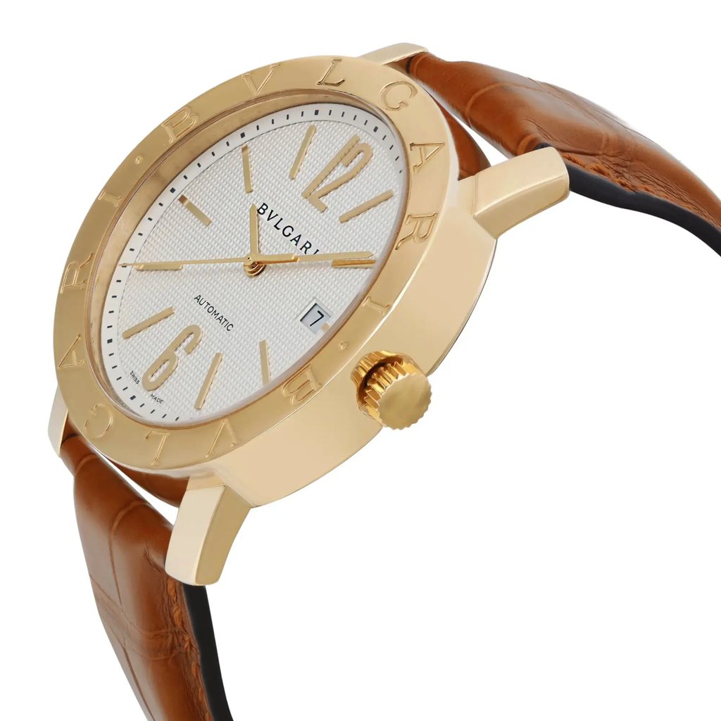 An image of a pre-owned Bvlgari men's wristwatch featuring a yellow gold case with a white textured dial. The watch is angled slightly to the right, highlighting the engraved brand name on the bezel and the date indicator at the 3 o'clock position. The timepiece has a brown leather strap, and the crown is prominently displayed on the right side. The image is taken from a close perspective, focusing on the watch's elegant design and details.