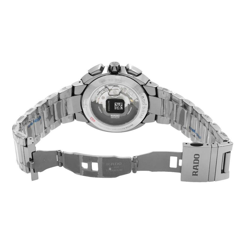An image of a new wristwatch shown from the back view with an open clasp. The watch is positioned centrally, with its metallic bracelet spread wide, showcasing the inner workings of the watch through a transparent case back. The angle is straight-on, capturing the intricate details of the movement, while the distance is close enough to highlight the craftsmanship and material quality.