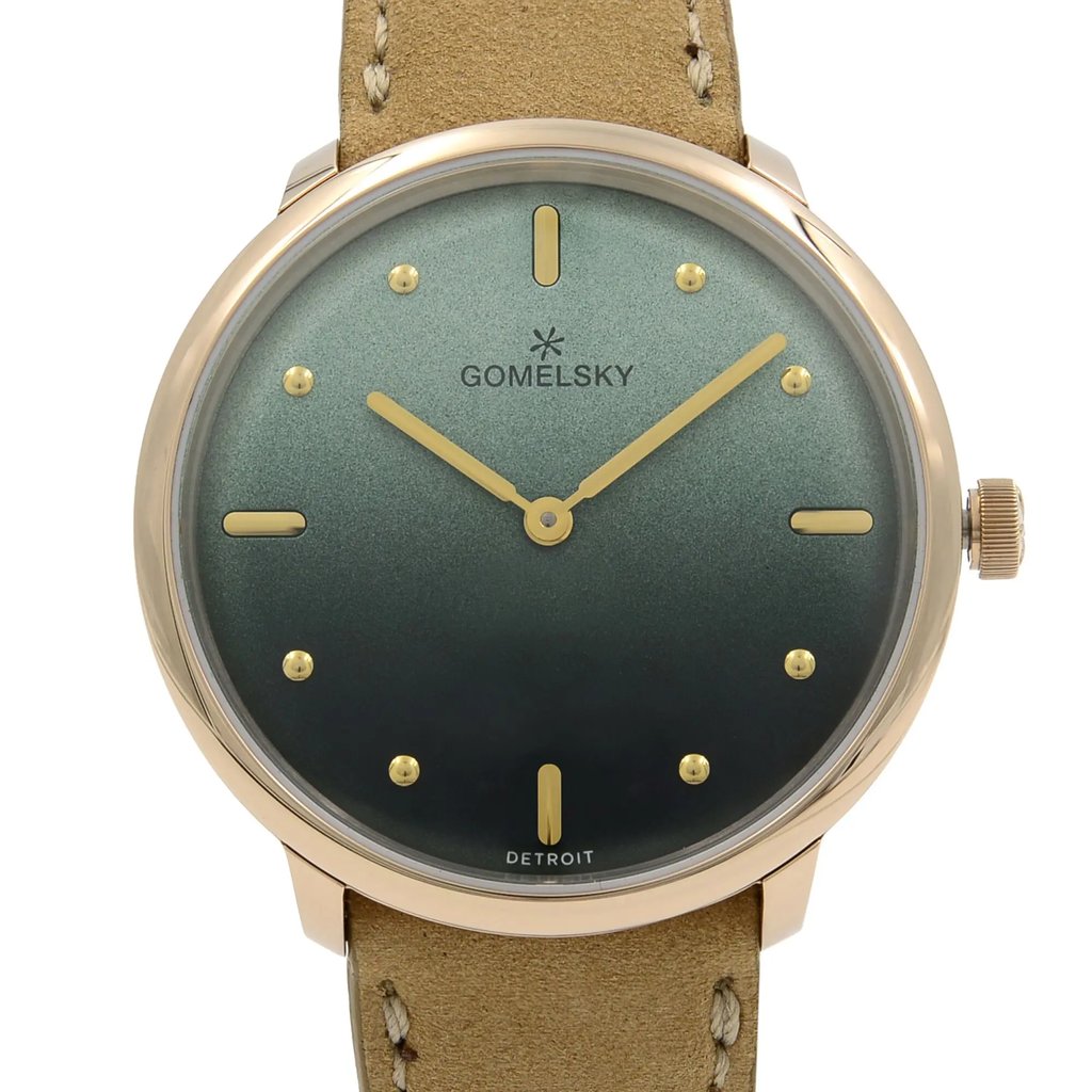 An image of a wristwatch taken from a front close-up angle, showcasing the unworn watch face. The watch features a green dial with gold hour markers and hands. The brand name "Gomelsky" is visible on the face, and the watch is complemented by a beige leather strap.