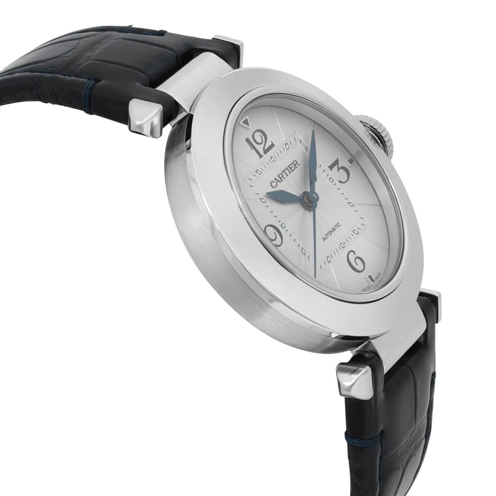 An image of a pre-owned men's Cartier wristwatch positioned at a slight angle, showcasing the side and partial face of the watch. The silver case and blue hands are prominently visible, complemented by a black leather strap. The angle highlights the watch's elegant design and craftsmanship, with a close-up focus that emphasizes its luxury details.