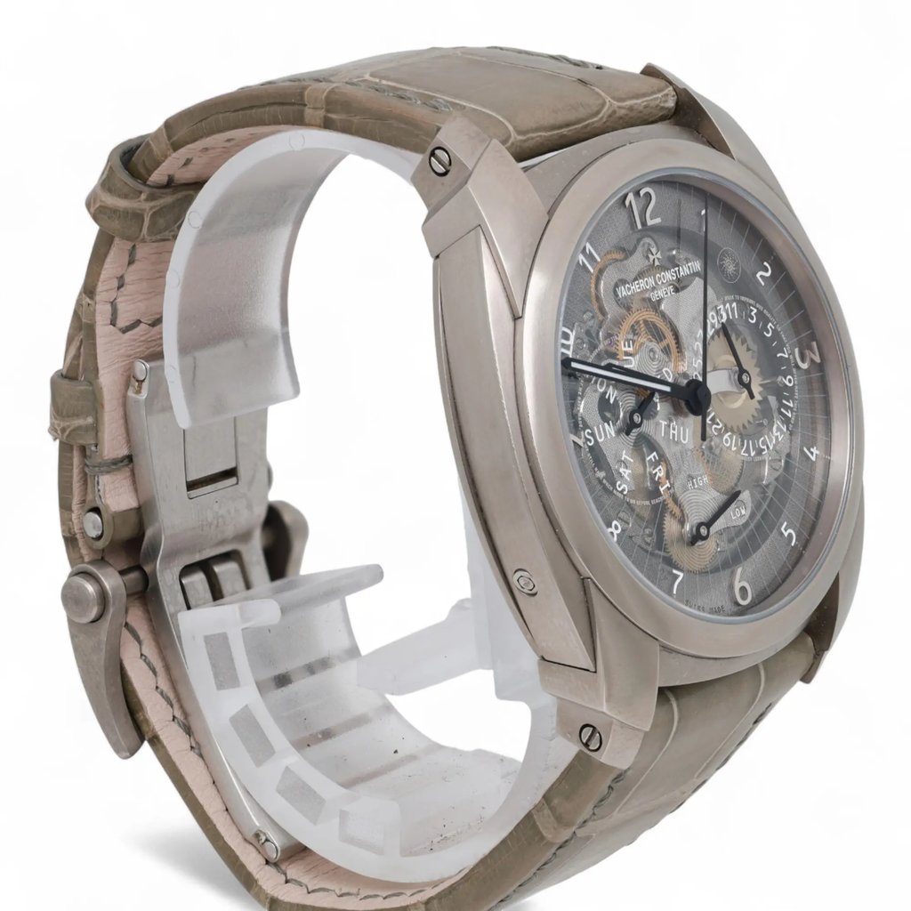 An image of a pre-owned men's Vacheron Constantin wristwatch, taken from a three-quarter angle, slightly above and to the left. The watch features a metallic case and a leather strap. The face displays luminous hands and intricate detailing. The angle highlights the side profile and the depth of the watch, with the strap partially open. The image is taken at a close distance, showcasing the craftsmanship and details of the timepiece.