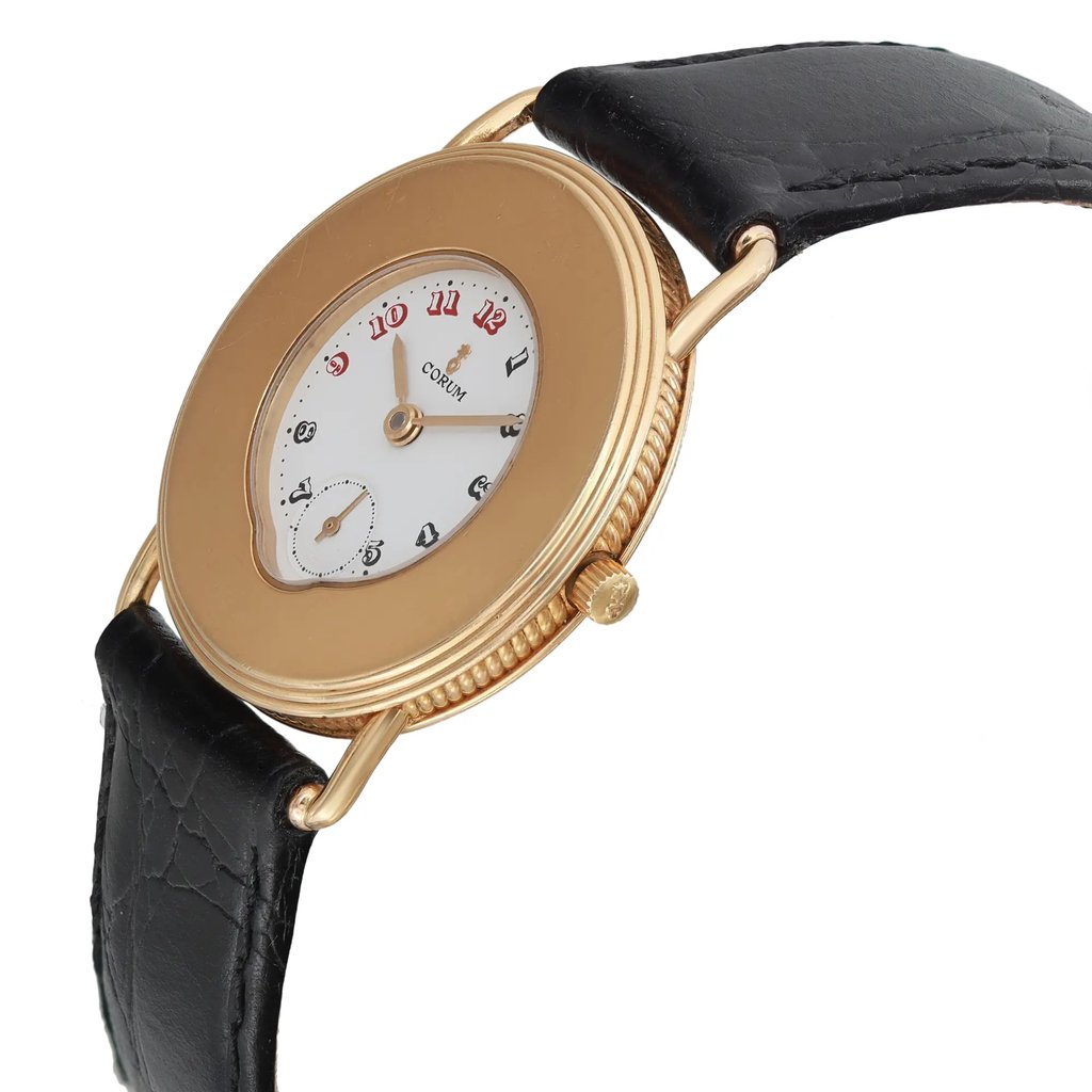 An image of a pre-owned wristwatch shown from a side profile view. The watch's crown is visible on the right side. The watch has a gold-colored case and a white dial with numerals, paired with a black leather strap. The angle highlights the textured edge of the case, and the shot is taken at a medium distance to capture these details clearly.