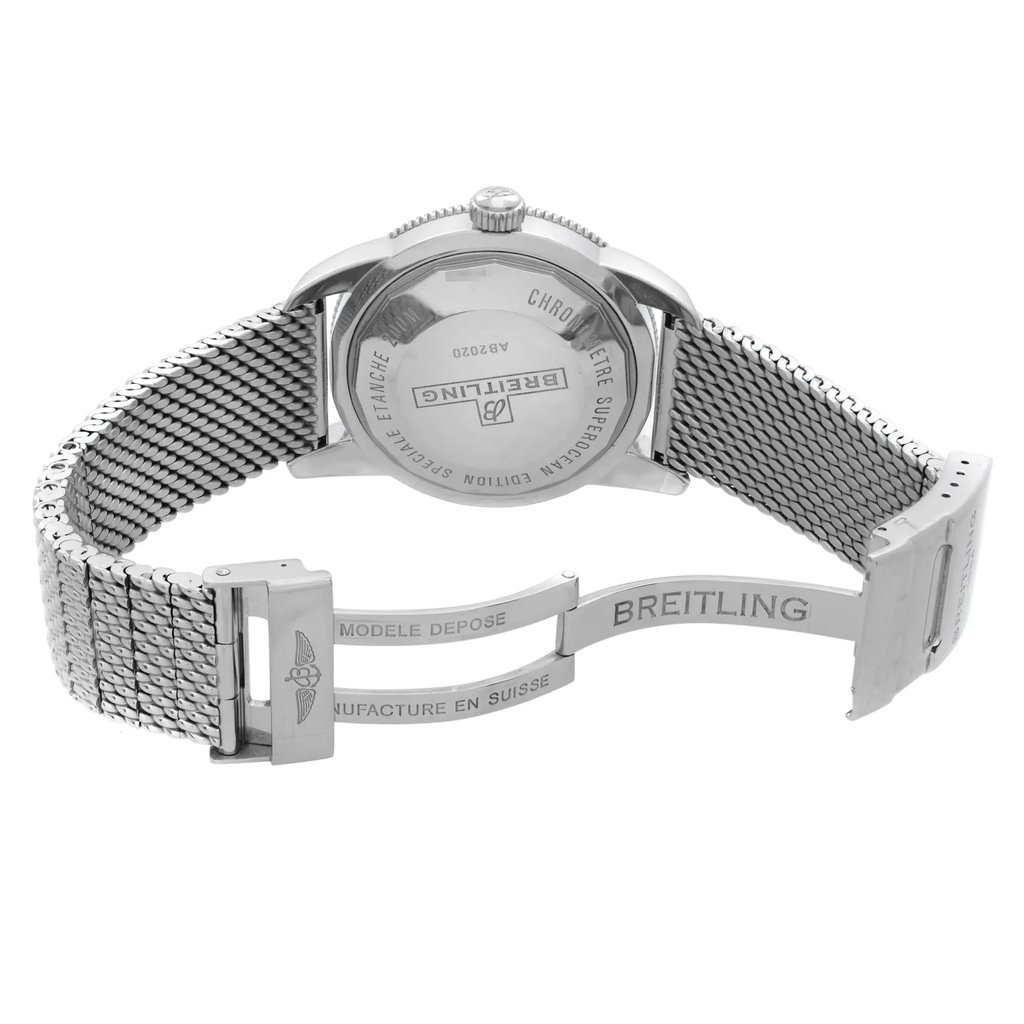 An image of a pre-owned Breitling men's wristwatch in a back view position with the clasp open. The watch is displayed at a slight left angle, showing the screwback stainless steel caseback and round shape. The stainless steel band has a mesh texture and leads to a fold-over clasp with flip lock safety showcasing the Breitling logo. The watch is photographed up close on a white background, capturing intricate details and the reflective surfaces of the metal components.