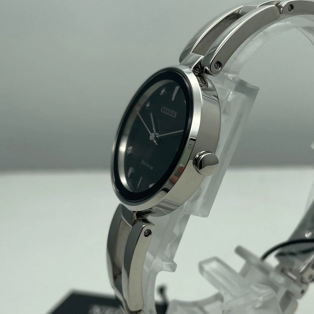 An image of a Wristwatch by Citizen. This Unworn item is designed for Women, featuring a Casual,Dress/Formal style. It has a Quartz movement and an Analog display with a Black dial color. The indices include Diamond Markers. The band is made of Stainless Steel and the case is made of Stainless Steel. The watch has a Round shape with a case size of 28 mm and a case thickness of 7 mm.