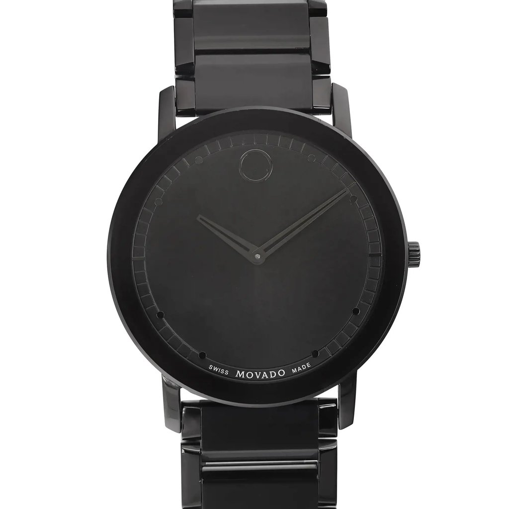 An image of a wristwatch taken from the front, showing a close-up of the watch face. The watch features a minimalist design with a dark, sleek appearance. The hands are simple and the hour markers are subtle, creating a clean and modern look. The watch is a display model, positioned directly facing the viewer, allowing for a full view of its design and details. The distance is close up, emphasizing the watch's aesthetic features.