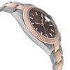 An image of a pre-owned men's Rolex wristwatch viewed from a side angle, slightly elevated, showcasing its two-tone metal bracelet and fluted bezel. The dark watch face features a date indicator and luminous hands, with the Rolex crown logo prominently displayed.