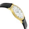 An image of a pre-owned wristwatch shown from a side profile view, opposite the crown, at a slight angle. The watch features a gold case and a white dial with black Roman numerals. The black leather strap is visible on both sides of the case, displaying a textured pattern. The photograph captures the watch at a close distance, highlighting its elegant design and details.