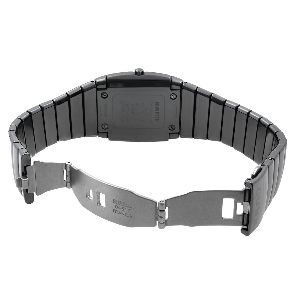 An image of a pre-owned wristwatch shown from the back view, displaying an open clasp. The watch is positioned horizontally, with the metal band splayed outwards. The angle provides a clear view of the back of the watch case and the bracelet links. The distance is close enough to capture the details of the clasp and the inscriptions on the back of the watch.