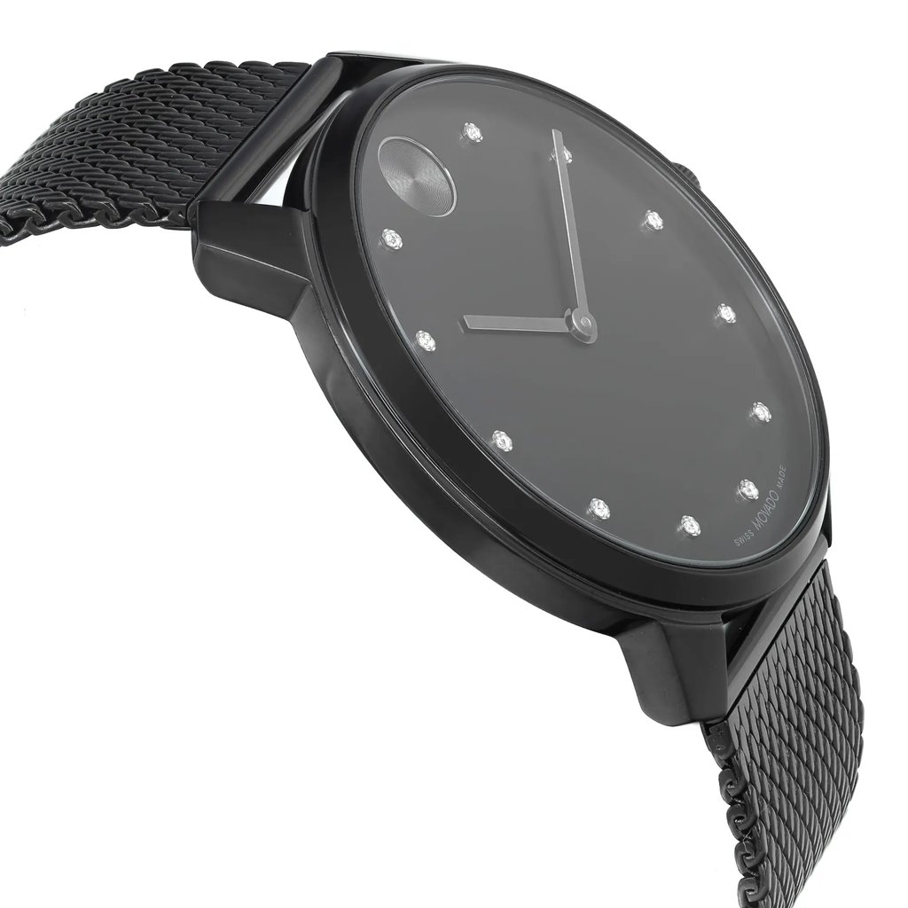 An image of a wristwatch taken from a side profile view, opposite of the crown. The watch is positioned at a slight angle, showcasing its sleek black mesh band and minimalist black face with crystal hour markers. The photo is taken at a close distance, highlighting the watch's new condition despite noted defects.
