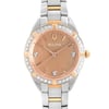 An image of a new Bulova women's wristwatch with a slight defect, presented in a front close-up shot that focuses on the watch face. The round dial is bronze-colored with a Mother of Pearl pattern, featuring diamond markers and stick indexes under a rose gold-tone bezel adorned with diamonds. The stainless steel band combines silver and rose gold-tone elements, and the watch is styled for dress/formal occasions. The distance and angle provide a clear view of the watch's details, with the face centered in the frame.