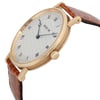 An image of a pre-owned Breguet men's luxury wristwatch, captured from a side profile angle showcasing the crown. The watch has a round 18k yellow gold case with minor signs of wear, a gold bezel, and a geometric silver dial with Roman numerals. It features a leather band with visible textures, suggesting a crocodile pattern. The hands of the watch are blued steel, and the Breguet logo is visible on the dial. The photo is taken at a close distance, emphasizing the watch's design and details.