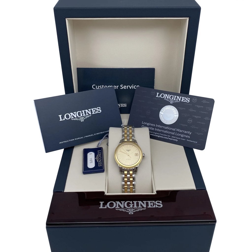 An image of a new wristwatch positioned centrally within an open box, surrounded by documents and warranty cards. The watch features a two-tone metal bracelet and a gold-colored dial. The box lid and documents are angled slightly backward, providing a full view of the contents. The image is taken from a straight-on perspective at a moderate distance, showcasing the brand name on the box and documents.