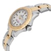 An image of a pre-owned wristwatch shown from a side profile view, highlighting the crown. The watch features a two-tone metal band with gold and silver links. Its face is partially visible, displaying a white dial with bold black markers. The watch bezel is gold, and the crown is prominently positioned on the right side. The angle captures the watch from a slightly elevated perspective, focusing on the details of the case and band.