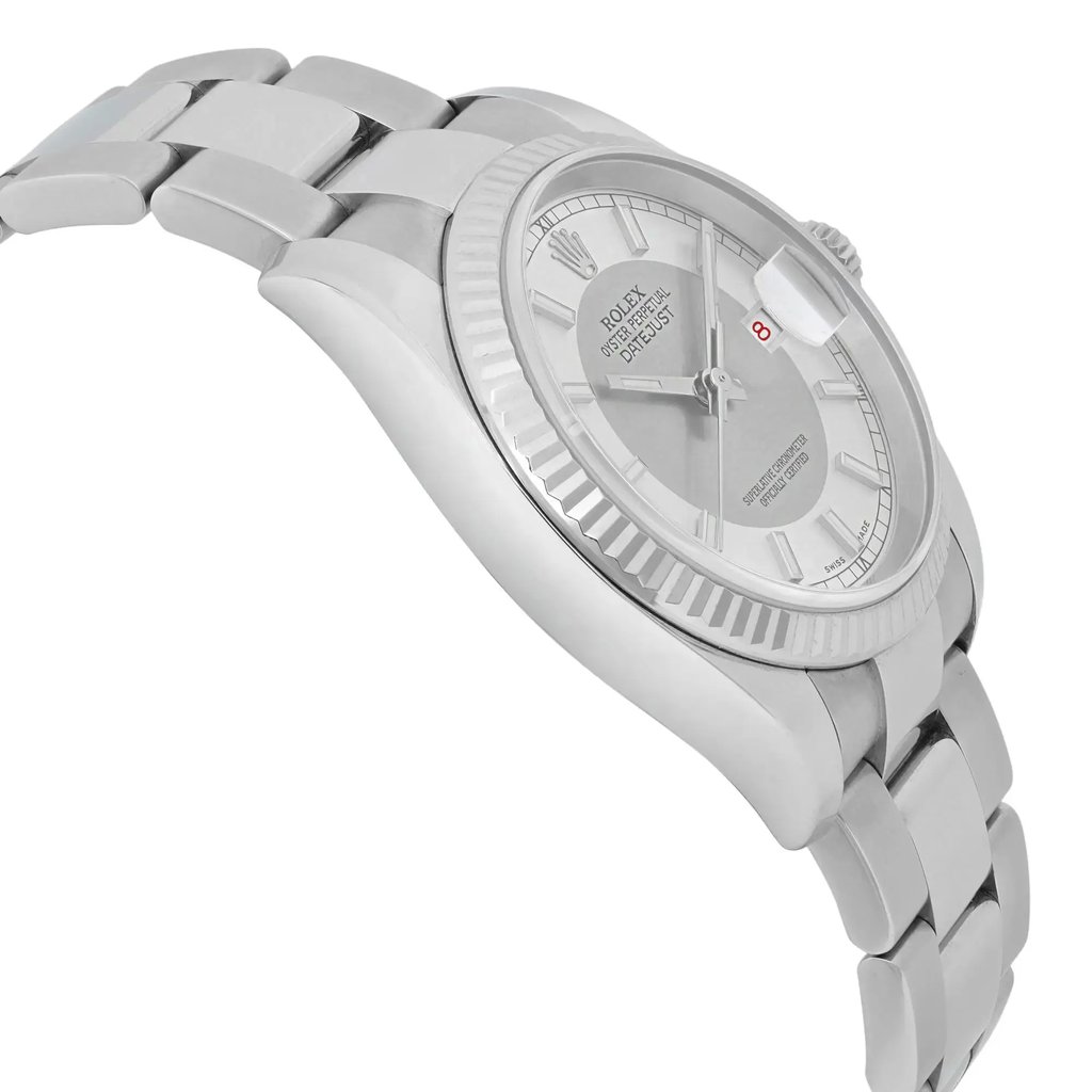 An image of a pre-owned men's Rolex wristwatch, viewed from a slight side angle, showcasing its silver-toned bracelet and case. The watch face features a date indicator and luminous hands, with a focus on the detailed bezel and crown. The watch is positioned at a close distance, highlighting its elegant design and craftsmanship.
