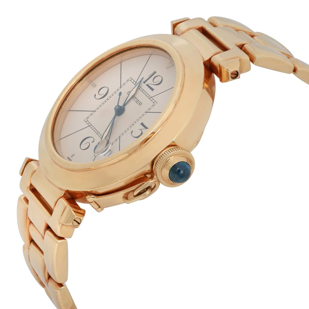 An image of a pre-owned Cartier men's wristwatch, viewed from a slightly elevated angle to the right. The watch features a gold-toned metal band and case, with a round face displaying a date indicator and luminous hands. The crown is adorned with a blue cabochon. The watch is positioned at a close distance, highlighting its elegant design and detailing.
