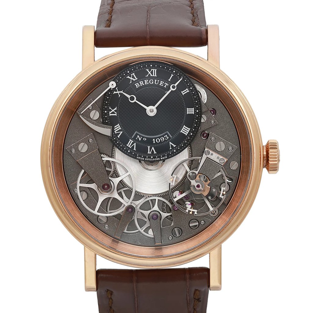 An image of a luxury men's Breguet wristwatch, viewed up close in a wristshot. The watch has a round, rose gold case with a gray dial, featuring intricate mechanical details and a power reserve indicator. The dial lacks hour marks and displays Roman numerals. The leather band is visible at the top and bottom, complementing the elegant design.