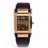 An image of a pre-owned women's Patek Philippe twenty-4 18K Rose Gold Diamond Chocolate Dial Ladies Watch 4920R wristwatch captured from a front-facing angle. The watch features a rectangular face with a chocolate dial, Roman numerals at the 12 and 6 positions, and diamond hour markers. The case is bordered with a double row of sparkling diamonds, and the watch is fitted with a dark leather strap. The image is taken at a close distance, highlighting the luxurious details and craftsmanship.