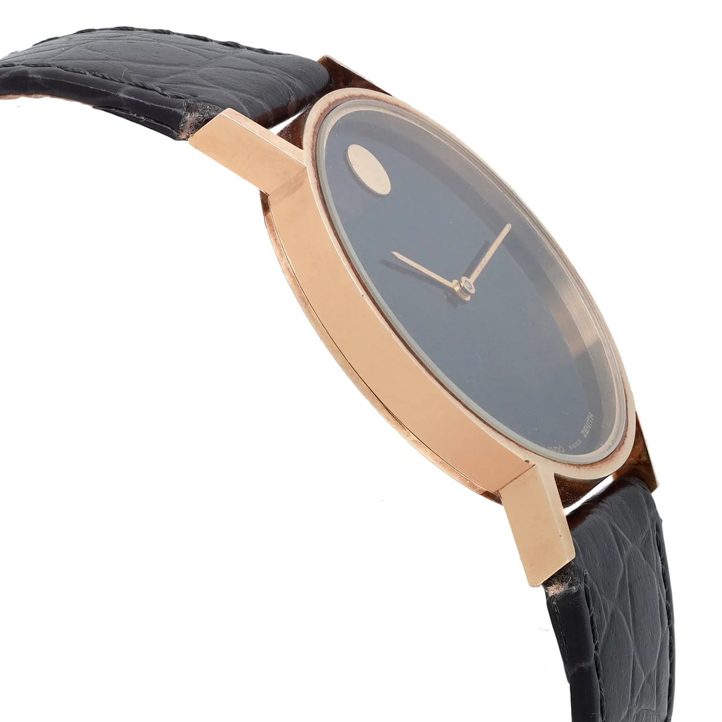 An image of a pre-owned wristwatch shown from a side profile view, opposite the crown. The watch has a sleek, gold-toned case and a dark face with minimalistic hands. The angle highlights the watch's thin profile and smooth design. The black leather strap features a textured pattern, adding a classic touch. The image captures the watch from a close distance, emphasizing its elegant and timeless style.