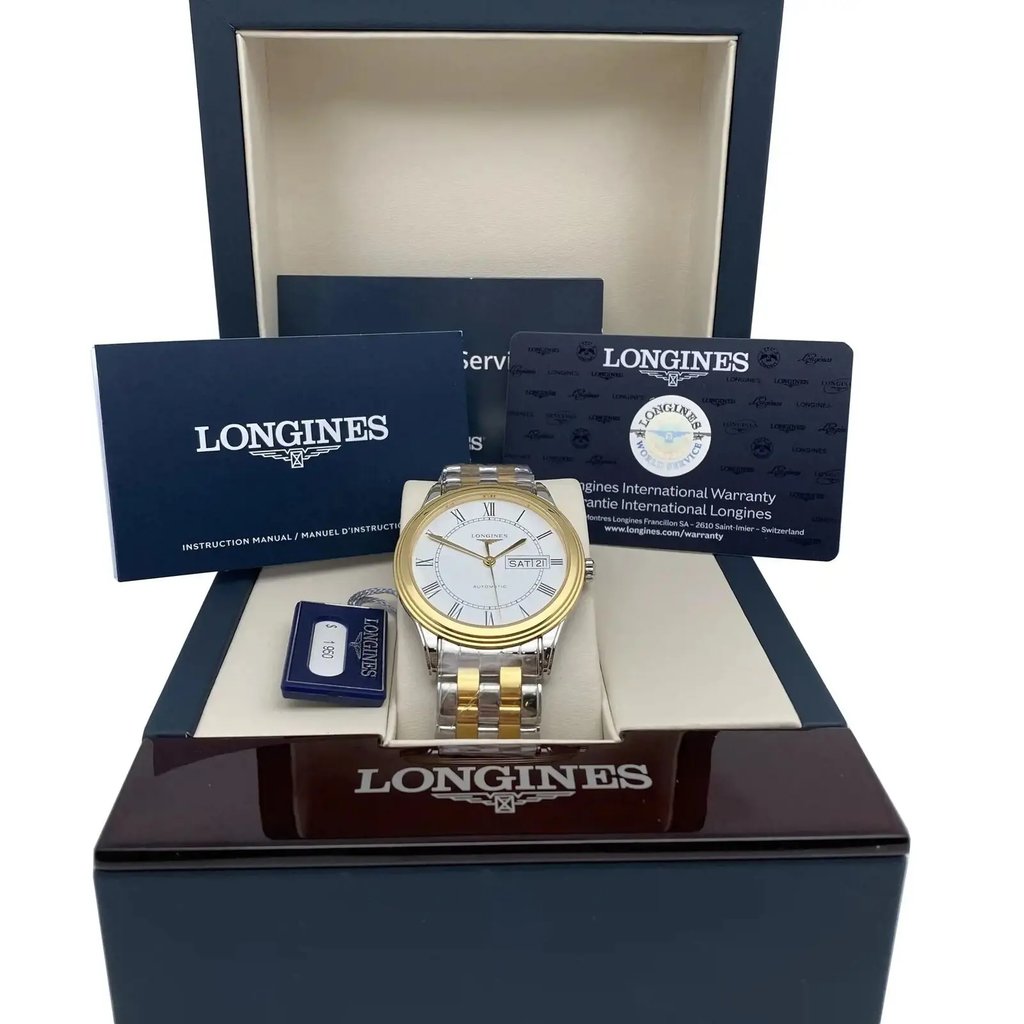 An image of a new wristwatch positioned centrally in an open display box. The watch features a two-tone metal bracelet and a white dial with a gold bezel. It is surrounded by branded documents and warranty cards. The photograph is taken from a slightly elevated angle, providing a full view of the watch and accompanying materials in the box, captured from a short distance to highlight the details.