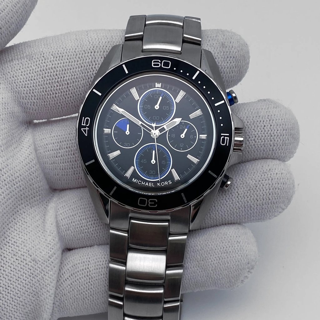 An image of a Wristwatch by Michael Kors. This Display Model item is designed for Men, featuring a Casual style. It has a Quartz movement and an Analog display with a Black dial color. The indices include 12-Hour Dial,Non-Numeric Hour Marks,Stick Indexes. The band is made of Stainless Steel and the case is made of Stainless Steel. The watch has a Round shape with a case size of 43 mm and a case thickness of 11 mm.
