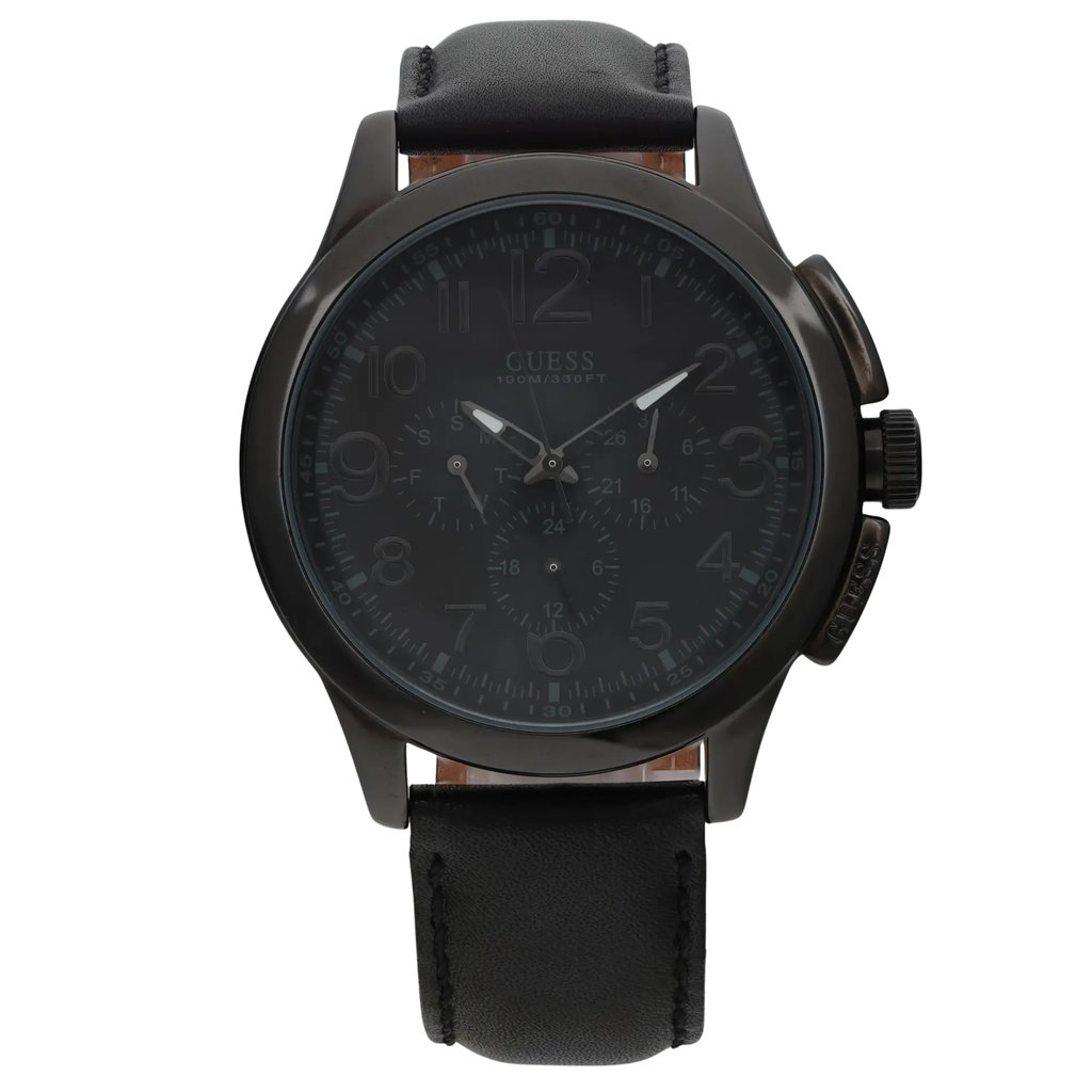 An image of a pre-owned men's GUESS wristwatch with a dark face and leather strap. The watch is positioned upright, facing directly towards the viewer, capturing a frontal view. It features a chronograph, date indicator, day/date display, luminous hands, and a small seconds subdial, all visible from this angle. The photo is taken at a close distance to highlight the details of the watch's face and features.