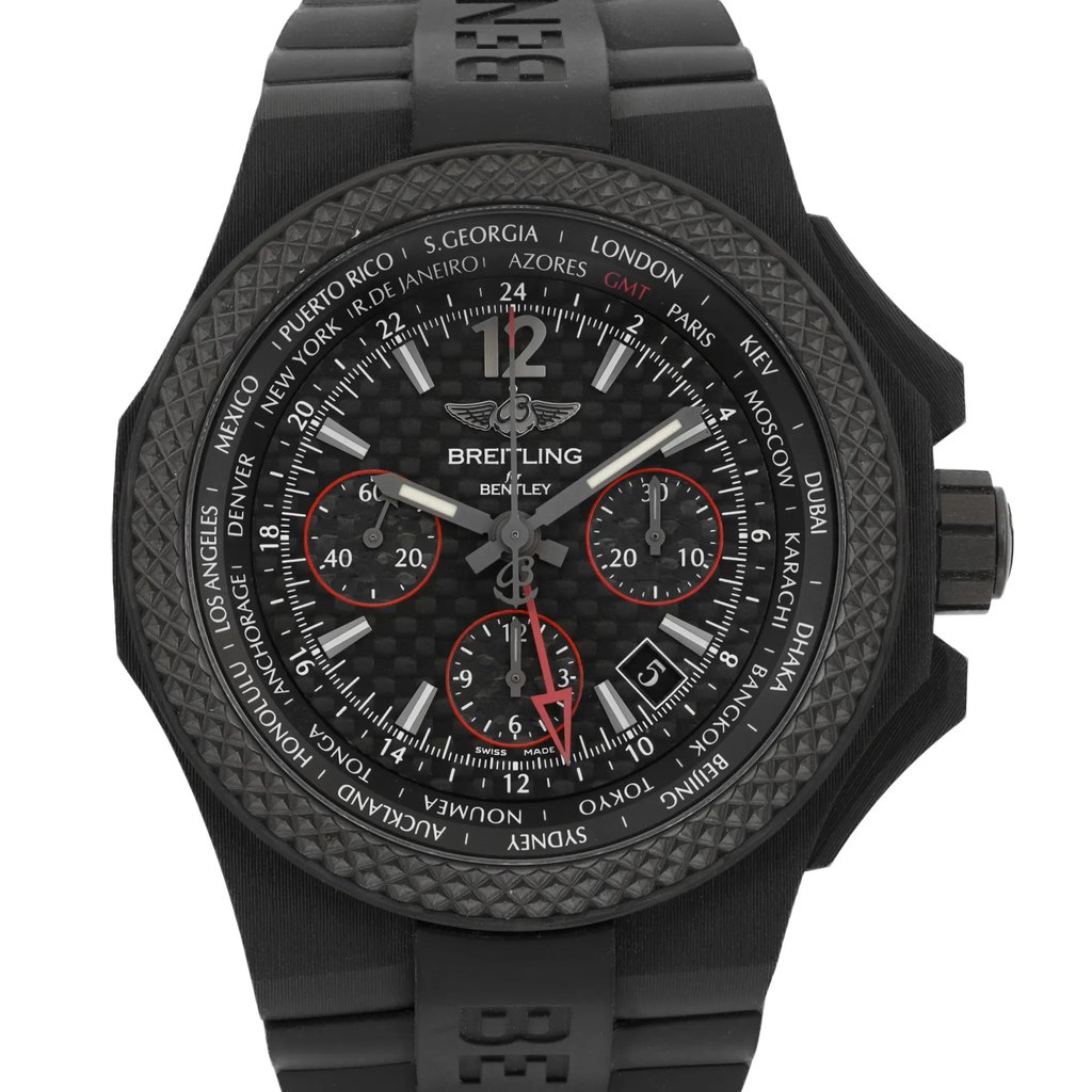 An image of a wristwatch showing a front close-up shot of the watch face. The watch features a black textured bezel, with a detailed dial displaying multiple time zones and chronograph subdials. The hands and markers are prominent, with red accents on the subdials. The strap is black and has a textured design. The shot highlights the intricate details and craftsmanship of the display model.