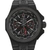 An image of a wristwatch showing a front close-up shot of the watch face. The watch features a black textured bezel, with a detailed dial displaying multiple time zones and chronograph subdials. The hands and markers are prominent, with red accents on the subdials. The strap is black and has a textured design. The shot highlights the intricate details and craftsmanship of the display model.