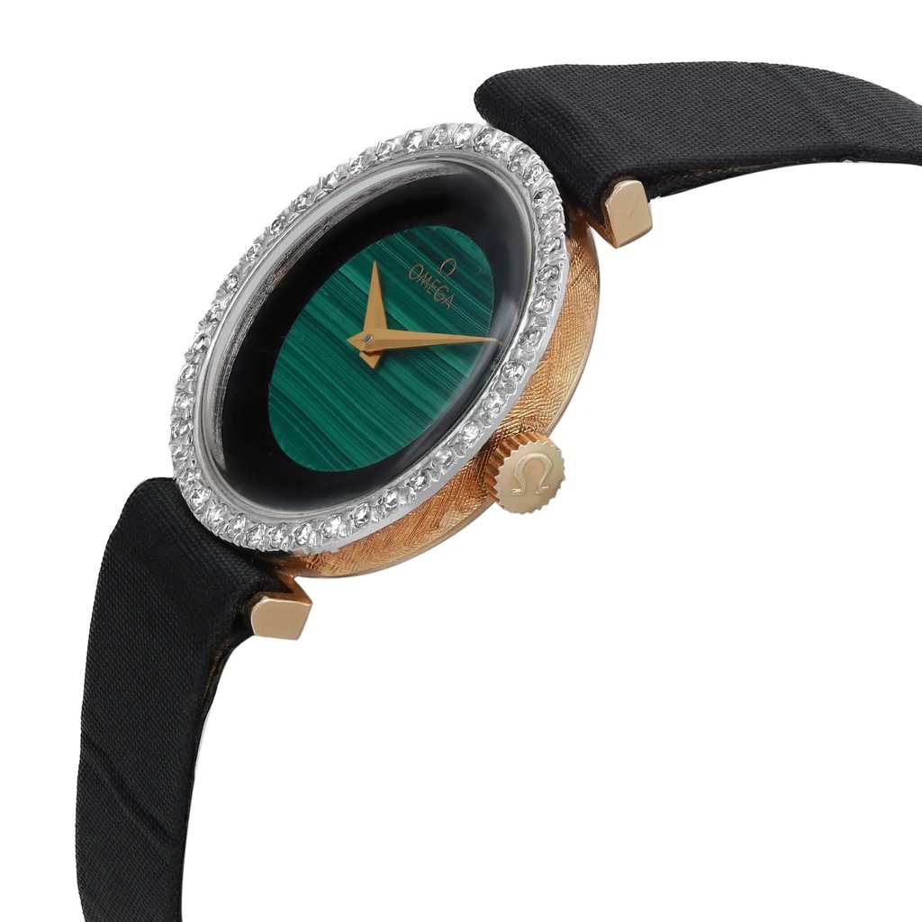 An image of a pre-owned wristwatch captured from a side profile view, highlighting the crown. The watch features a gold-toned case with a textured finish, adorned with a bezel encrusted with clear stones. The dial is a striking green with gold-toned hands. The black strap is partially visible, and the crown, bearing a logo, is prominently displayed. The angle shows the watch slightly tilted, offering a detailed view of its elegant design.
