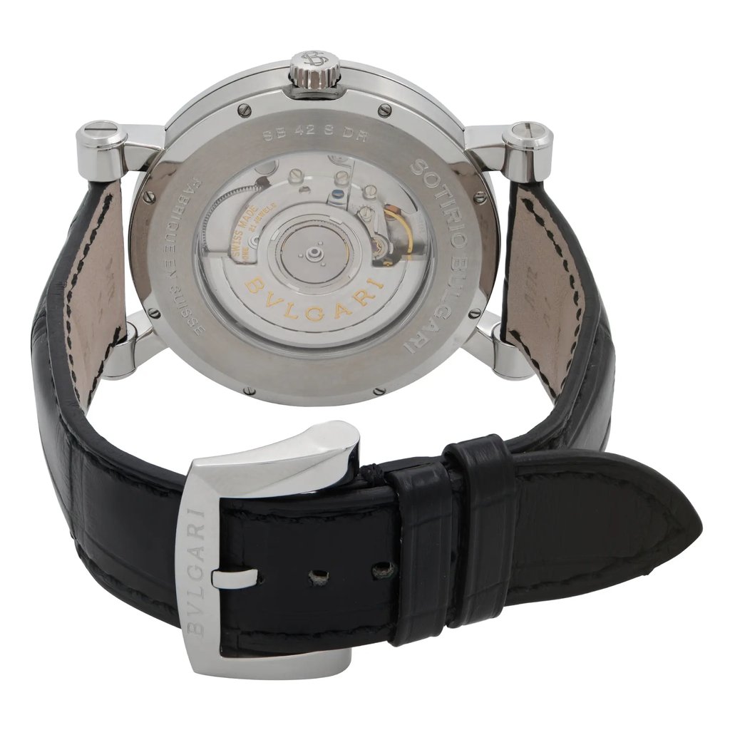 An image of a wristwatch showcasing the back view, highlighting the intricate mechanical movement through a transparent case back. The watch is positioned upright with the clasp partially open, displaying the black leather strap prominently. Photographed at a close distance, the angle offers a detailed look at the internal components and the engraved brand name on both the case and clasp. The watch is a display model, appearing in pristine condition.