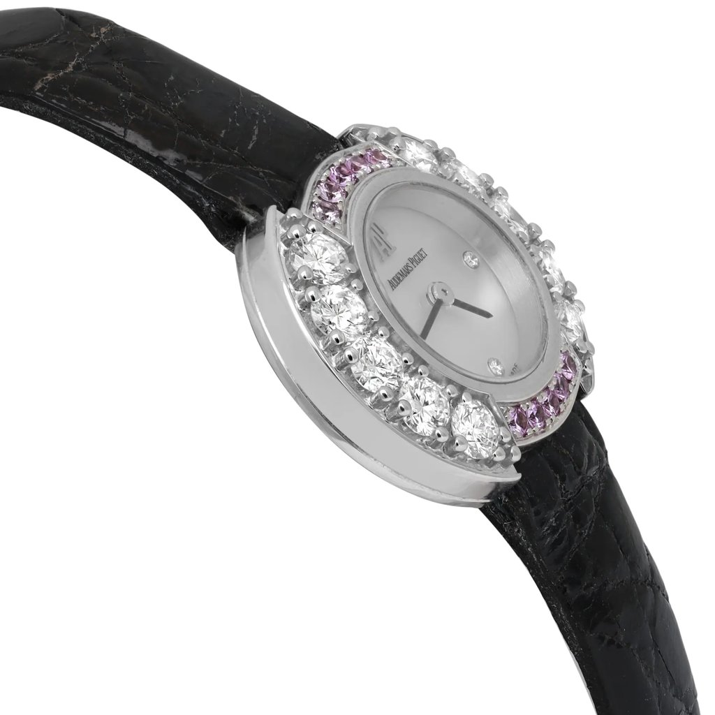 An image of a pre-owned Audemars Piguet women's wristwatch positioned at a slight angle, showcasing the watch face and part of the strap. The watch has a round MOP dial surrounded by sparkling diamonds and purple gemstones. The black leather strap is partially visible. The image captures the watch from a close-up perspective, highlighting its elegant details and luxurious design.
