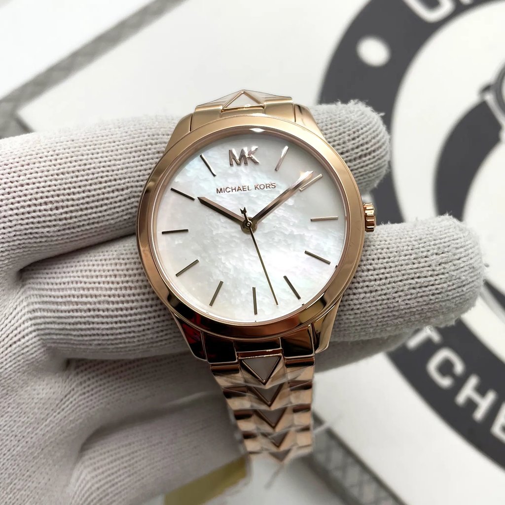An image of a Wristwatch by Michael Kors. This Display Model item is designed for Women, featuring a Dress/Formal style. It has a Quartz movement and an Analog display with a Silver dial color. The indices include 12-Hour Dial,Stick Indexes. The band is made of Stainless Steel and the case is made of Stainless Steel. The watch has a Round shape with a case size of 38 mm and a case thickness of 7 mm.