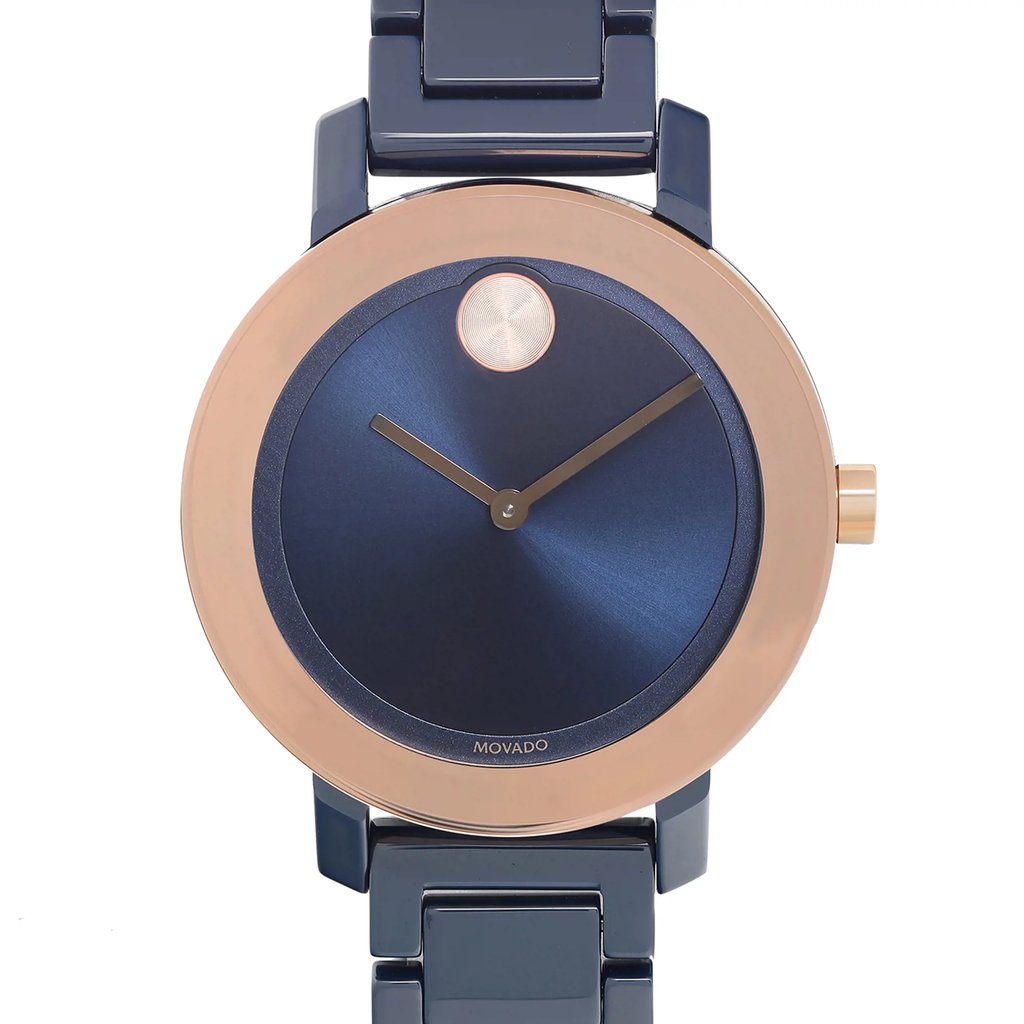 An image of a wristwatch taken from a front close-up angle, showcasing the watch face. The watch features a sleek, dark blue dial with minimalistic design, complemented by a metallic rose gold bezel. The timepiece is a display model, and the brand name is visible at the bottom of the dial.