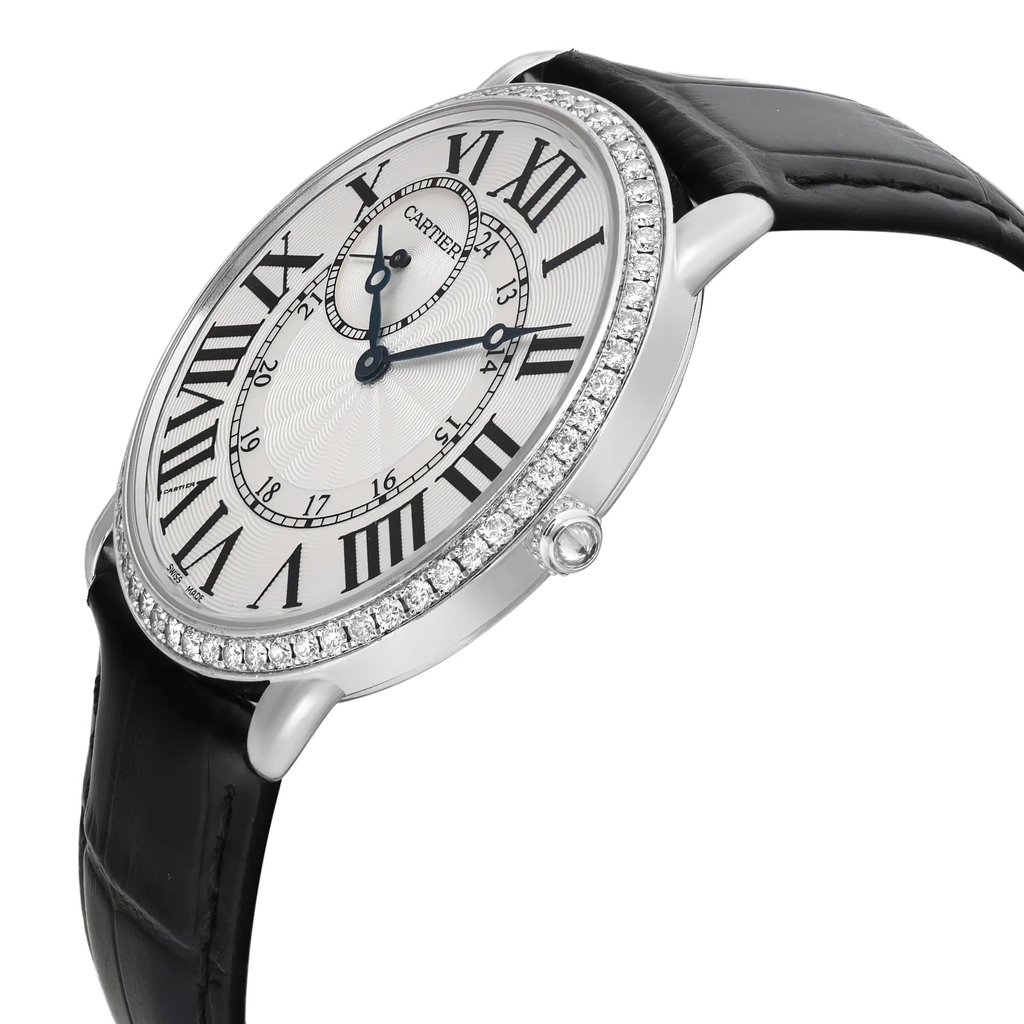 An image of a pre-owned wristwatch taken from a side profile view, showcasing the crown prominently. The watch features a round face with Roman numerals and a diamond-studded bezel. The black leather strap is partially visible, and the photo is taken at a close distance, highlighting the details and craftsmanship of the timepiece.