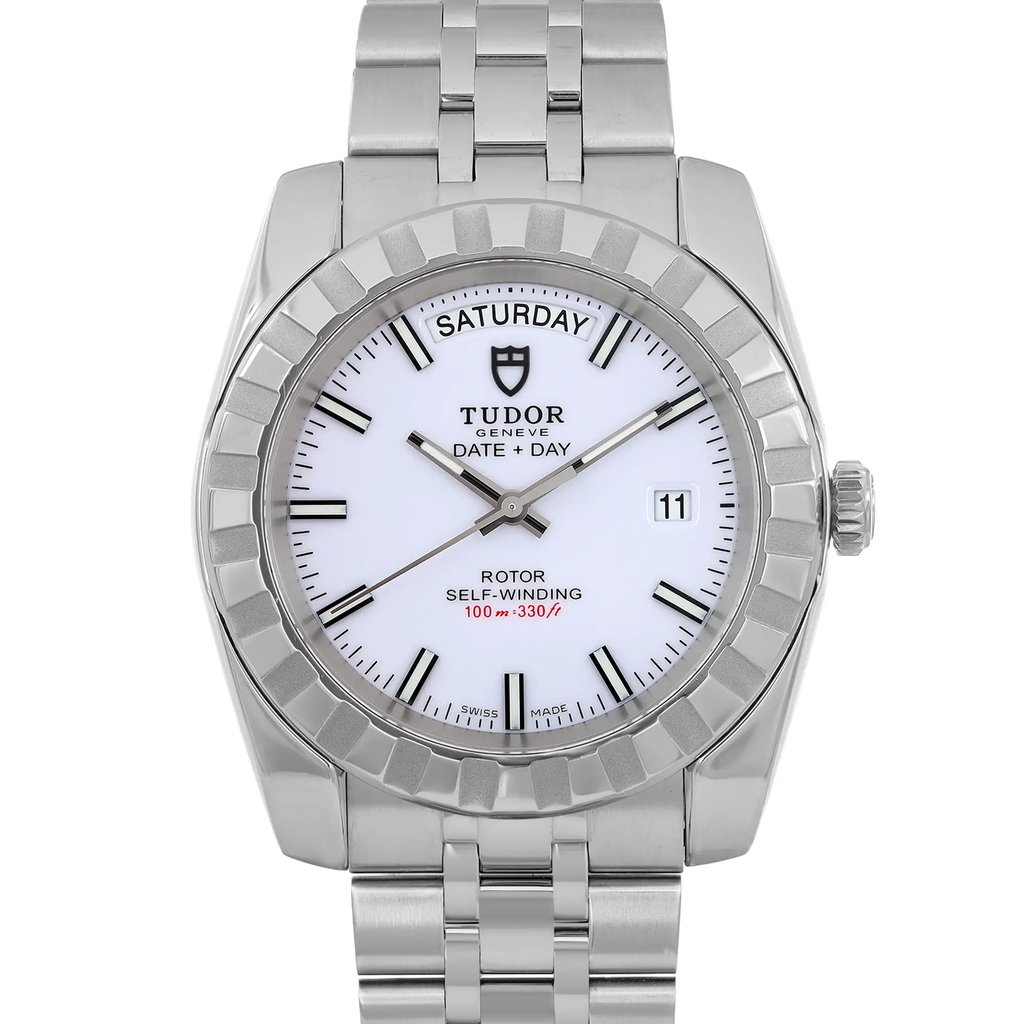 An image of a pre-owned men's TUDOR wristwatch, featuring day/date display and luminous hands. The watch is positioned upright, facing the viewer directly, showcasing its steel metal bracelet and white dial. The photograph is taken at a close angle, capturing the details of the watch face and bezel clearly.