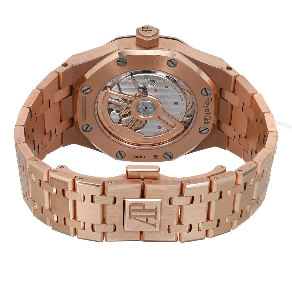 An image of a pre-owned men's Audemars Piguet wristwatch, viewed from the back at a slight angle. The watch features a rose gold case with an octagonal shape and an exhibition caseback, revealing the intricate internal mechanism. The band, also in rose gold, is equipped with a double-locking fold-over clasp. The image shows the watch positioned upright with the clasp closed, highlighting the brand's logo. The condition is classified as good, and the watch includes features like luminous hands.