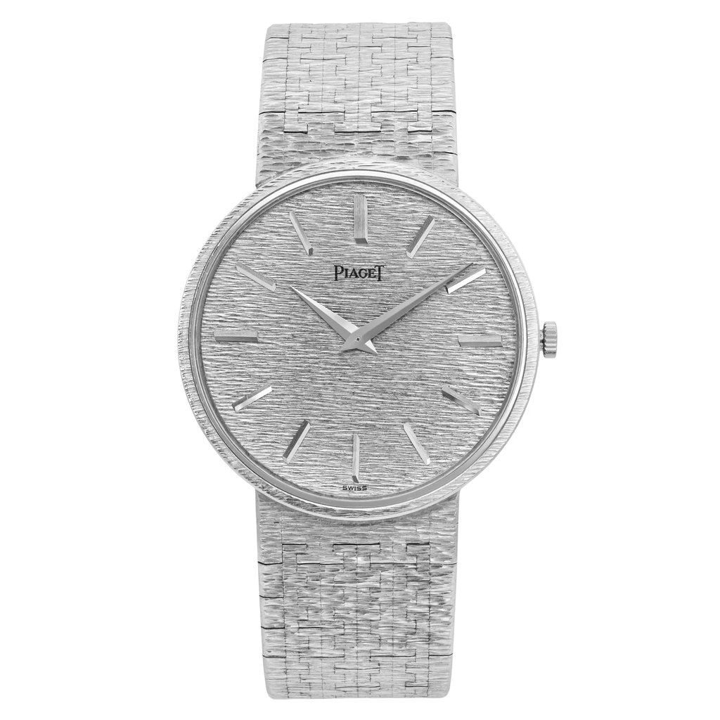 An image of a pre-owned Piaget Classic 32MM 18K White Gold Silver Dial Mechanical unisex adult wristwatch. The watch is positioned upright, showing a front-facing view. The angle is directly centered, capturing the full face and band of the watch. The distance is close-up, highlighting the textured silver dial and sleek silver markers, along with the matching textured band.