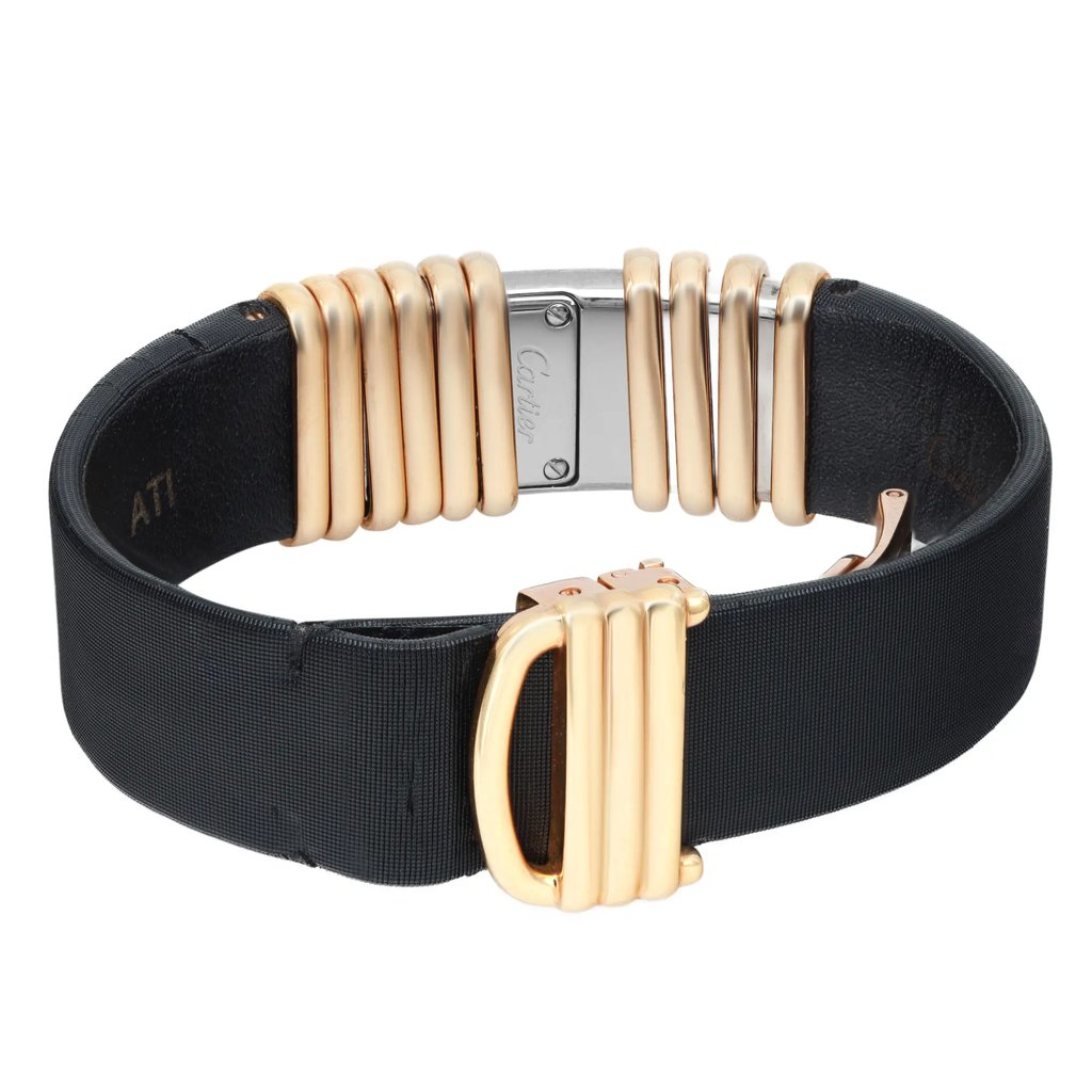 An image of a pre-owned wristwatch viewed from the back at a close distance, focusing on the clasp. The watch features a black strap with gold-tone links and a silver clasp. The brand name is engraved on the clasp, adding an elegant detail to the design.