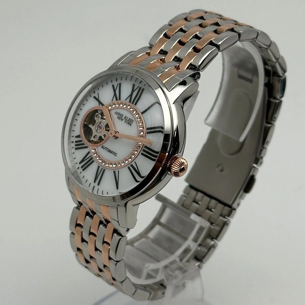 An image of a Wristwatch by Anne Klein. This Display Model item is designed for Women, featuring a Dress/Formal style. It has a Mechanical (Automatic) movement and an Analog display with a White dial color. The indices include 12-Hour Dial,Easy to Read/Large Numerals,Roman Numerals. The band is made of Stainless Steel and the case is made of Stainless Steel. The watch has a Round shape with a case size of 36 mm and a case thickness of 13 mm.