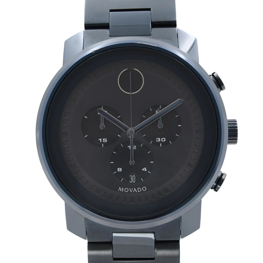 An image of a pre-owned wristwatch viewed from the front in a close-up shot. The watch has a sleek, dark dial with three subdials and minimalistic hour markers. The brand name is visible at the bottom of the watch face. The timepiece features a metal band and side buttons are visible on the right.