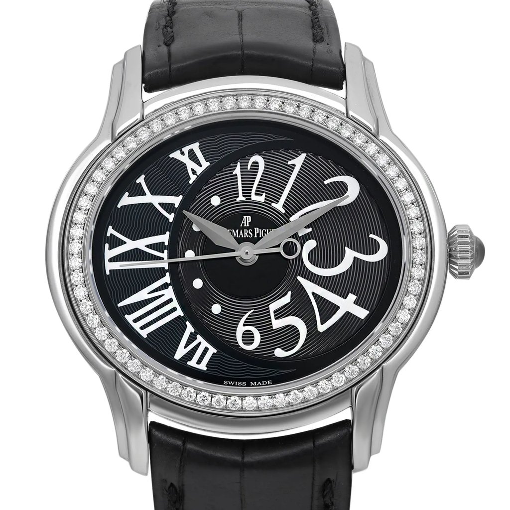 An image of a pre-owned wristwatch, shown in a front close-up shot focusing on the watch face. The watch features a polished silver case with a diamond bezel. The black dial displays large, overlapping white numerals and sleek silver hands. The elegant black leather strap is partially visible at the top and bottom of the image.