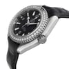 An image of a pre-owned wristwatch taken from a side profile view, showcasing the crown prominently. The watch has a black dial with silver hour markers and hands. The bezel is encrusted with sparkling stones, adding a touch of elegance. The watch strap is black and textured, complementing the sleek design. The angle provides a clear view of the watch's thickness and detailed craftsmanship.