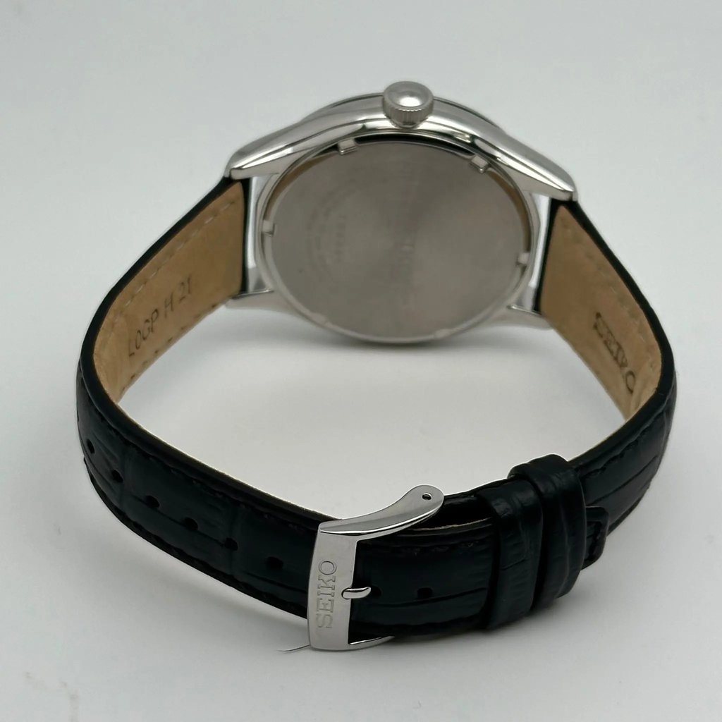 An image of a Wristwatch by Seiko. This Display Model item is designed for Men, featuring a Casual style. It has a Quartz movement and an Analog display with a Black dial color. The indices include 12-Hour Dial,Arabic Numerals,Non-Numeric Hour Marks. The band is made of Leather and the case is made of Stainless Steel. The watch has a Round shape with a case size of 42 mm and a case thickness of 11 mm.