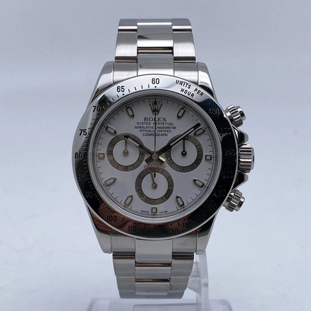 An image of a pre-owned men's Rolex Daytona Stainless Steel White Index Dial Automatic Men Watch 116520 positioned upright on a stand, captured from a frontal angle at a moderate distance. The watch features a chronograph with three subdials, luminous hands, and a small seconds subdial, set against a polished metal bracelet.