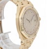 An image of a pre-owned women's Audemars Piguet wristwatch, taken from a slight side angle. The watch features a yellow gold case and bracelet, with a diamond-encrusted bezel. The dial is also set with diamonds and includes a date indicator at the 3 o'clock position. The watch is positioned upright, showcasing its luxurious design, and the image is captured from a close distance to highlight the intricate details.